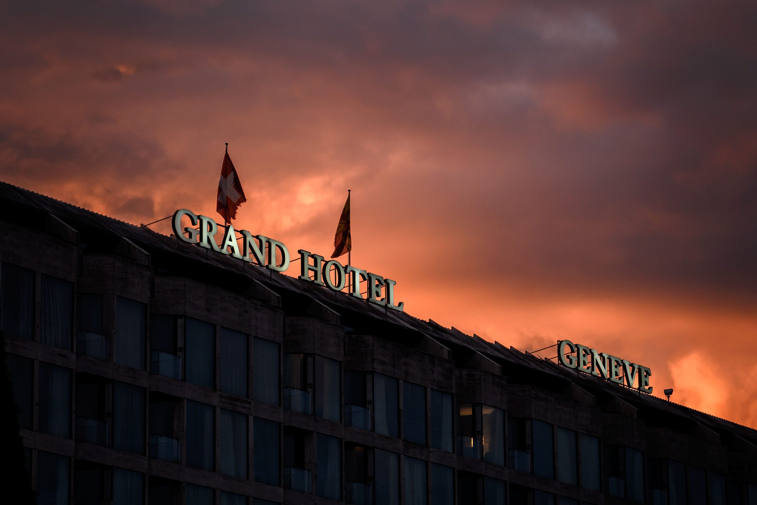 A picture taken on July 14, 2020 in Geneva shows the sign of the Fairmont Grand Hotel Geneva after sunset as luxury Geneva hotels are facing 'life-threatening' corona crunch. - Behind its deep-red awnings, Richemont's blinds have been closed since July, after the pandemic left the  usually bustling five-star Geneva hotel starved for high-paying customers. Now, after a 